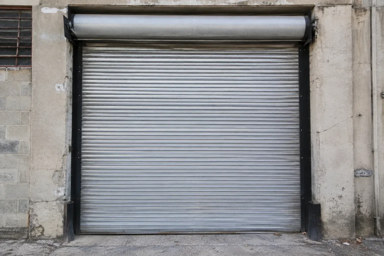 Closed metal rolling shutter in a weathered warehouse opening. — Commercial Rolling Door Repair, Markham