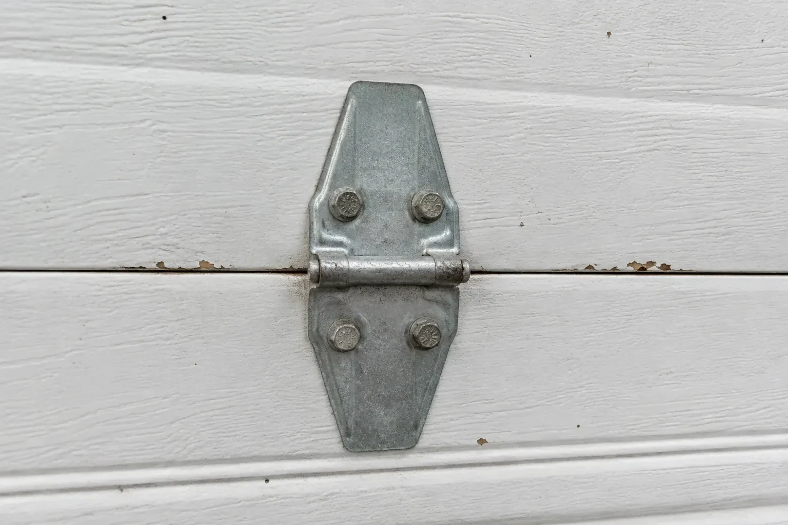 Metal center hinge across a seam in a white sectional garage door. — Garage Door Hinge Replacement, Markham